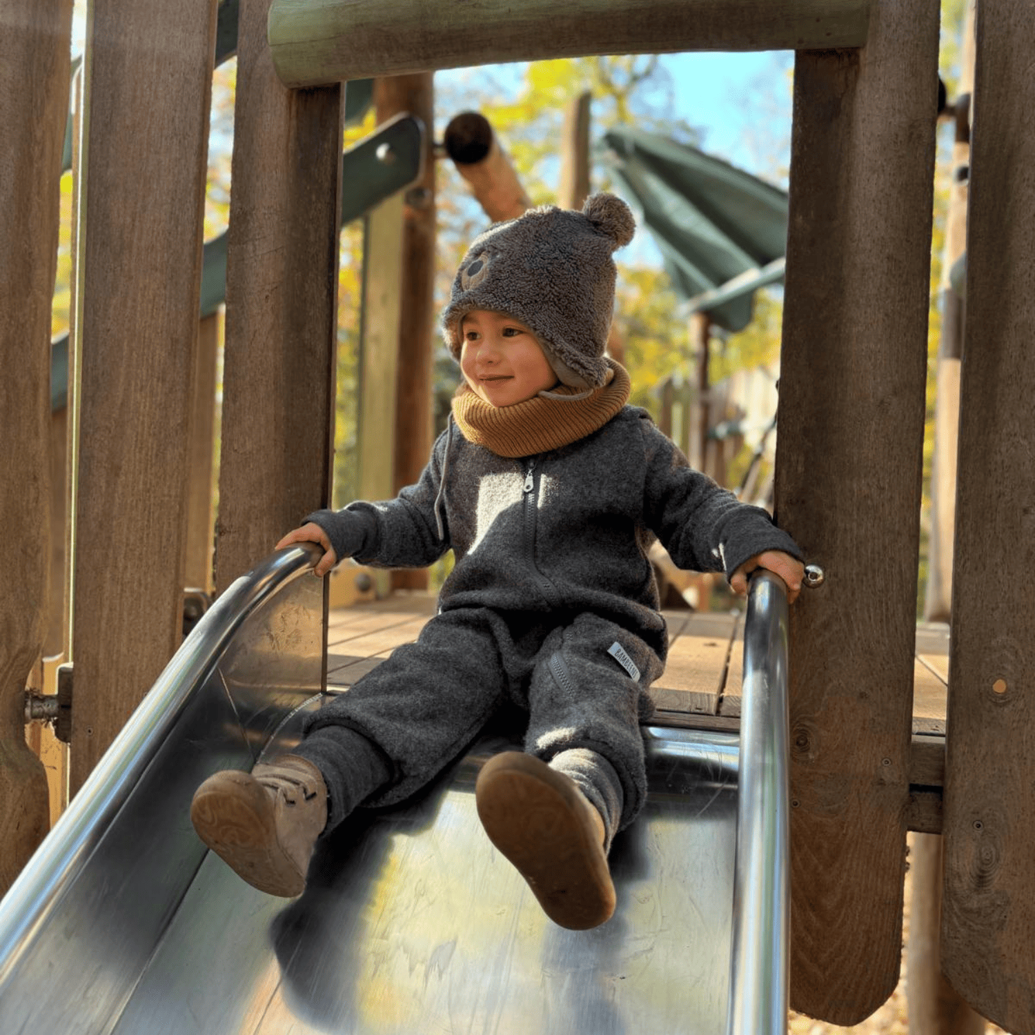 Kind in grauem Walkoverall- Sonne Mond und Regenbogen- Bambeeni Walkoverall für Babys & Kinder aus 100% Schurwolle und Baumwollinnenfutter