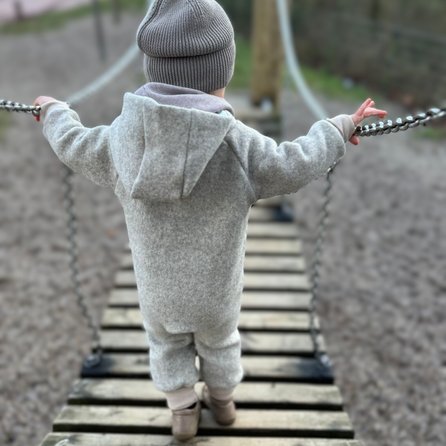 Kind in beigem Walkoverall- Herzen- Bambeeni Walkoverall fuer Babys & Kinder aus 100% Schurwolle und Baumwollinnenfutter