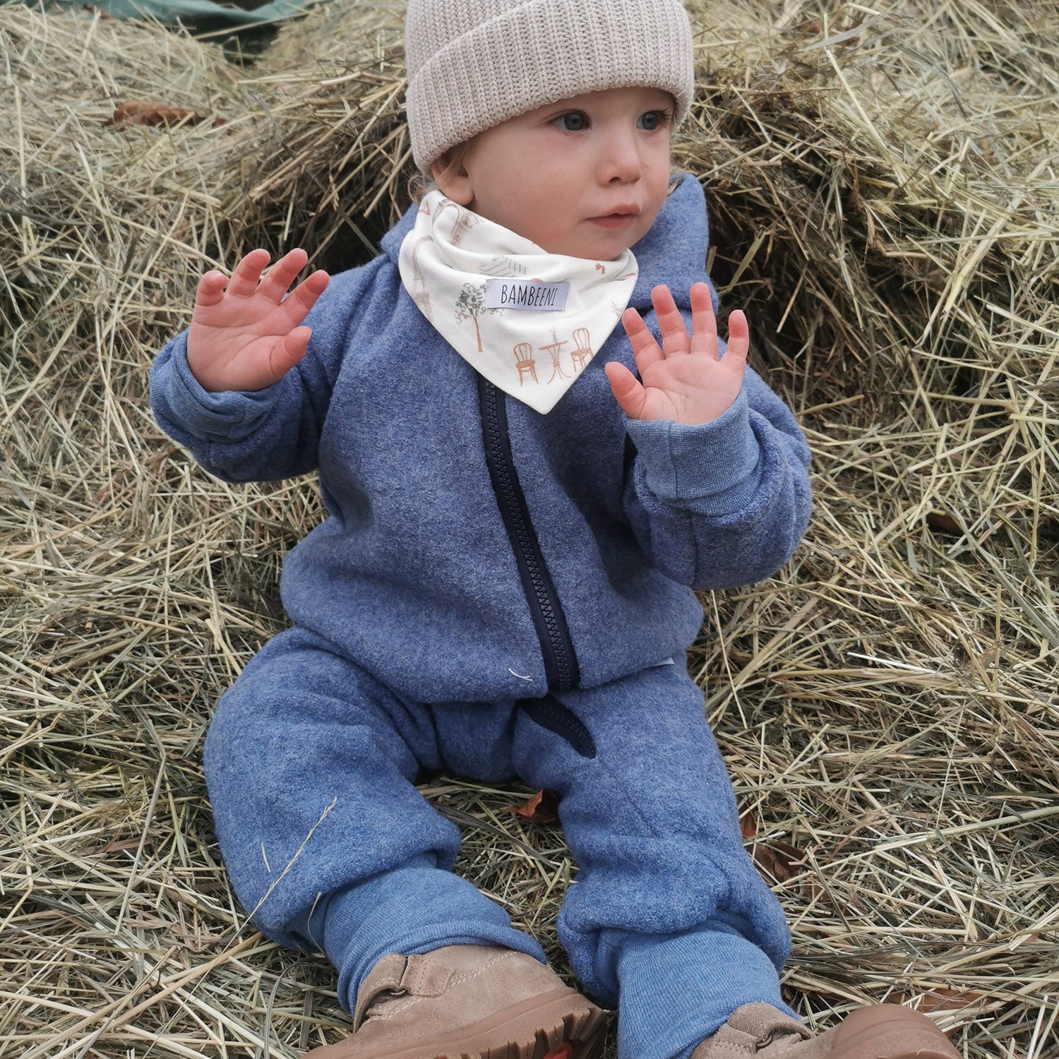 Kind in blauem Walkoverall- Paris- Stroh- Bambeeni Walkoverall fuer Babys & Kinder aus 100% Schurwolle und Baumwollinnenfutter